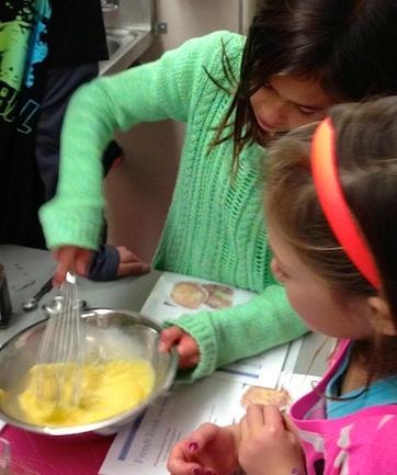 Children whisking eggs together in a Wise Way nutrition cooking class